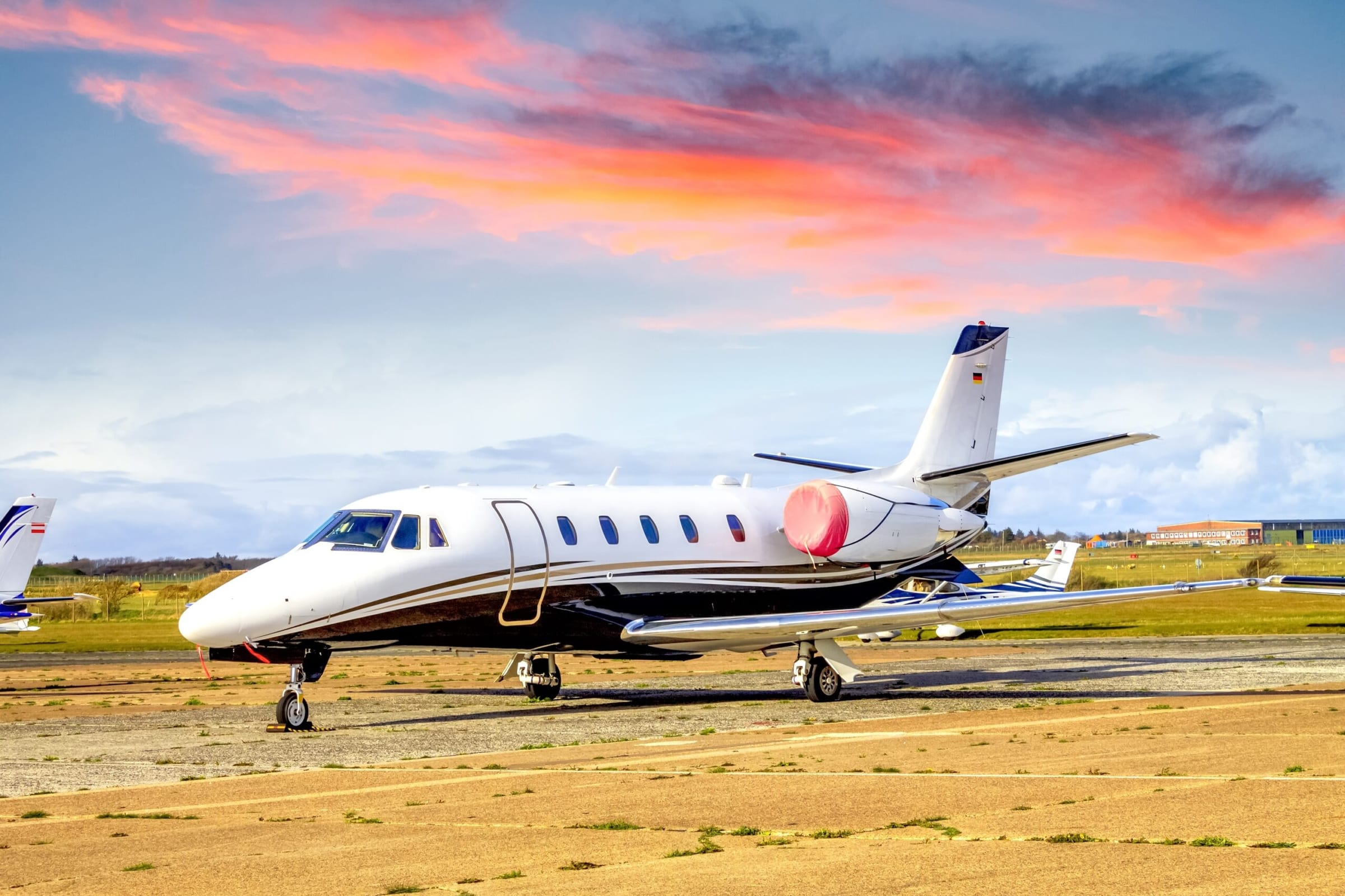 Cessna Citation with engine covers on parked at airport Sylt, Germany, with orange sky above