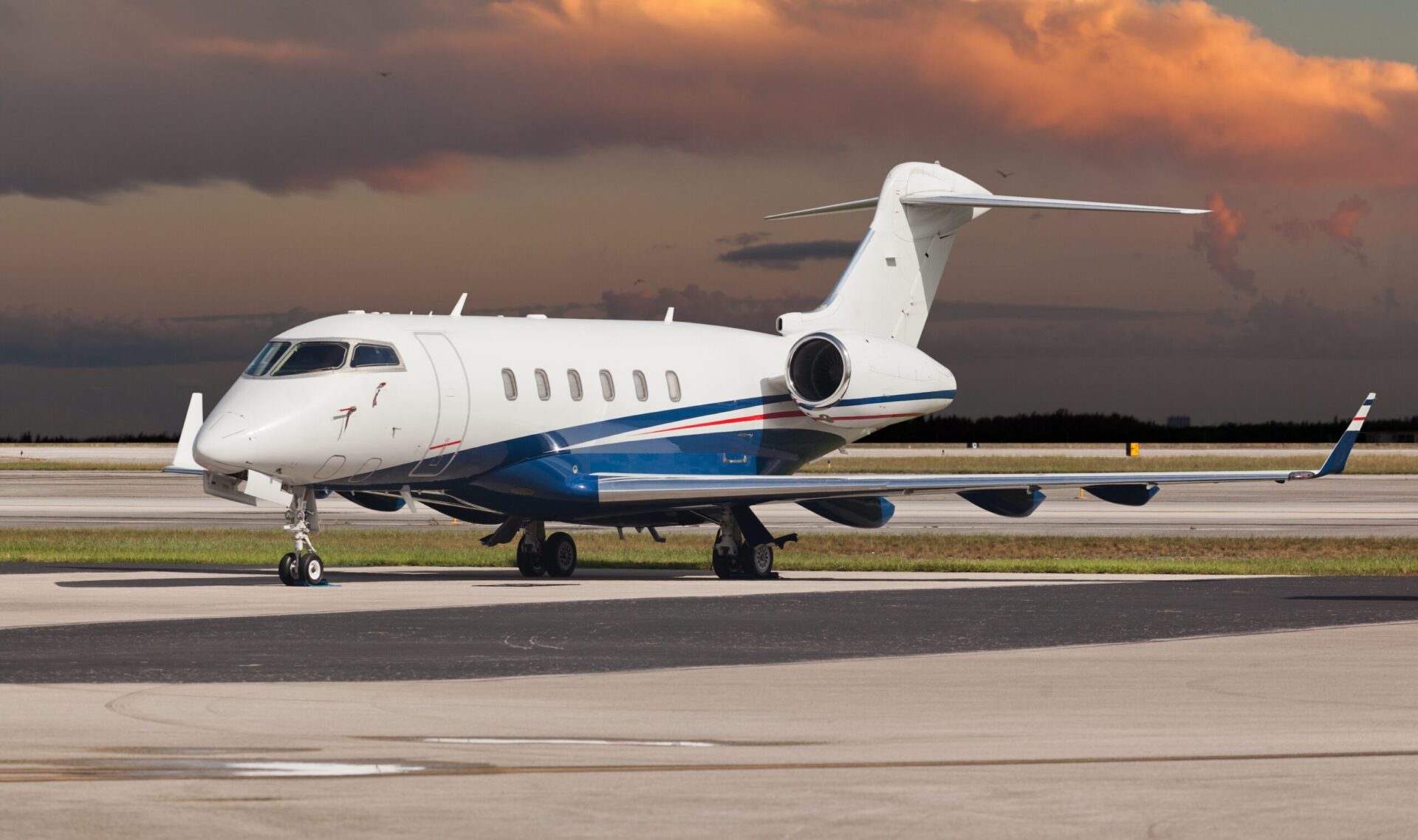 Bombardier Challenger 350 parked on the ramp with orange sky behind